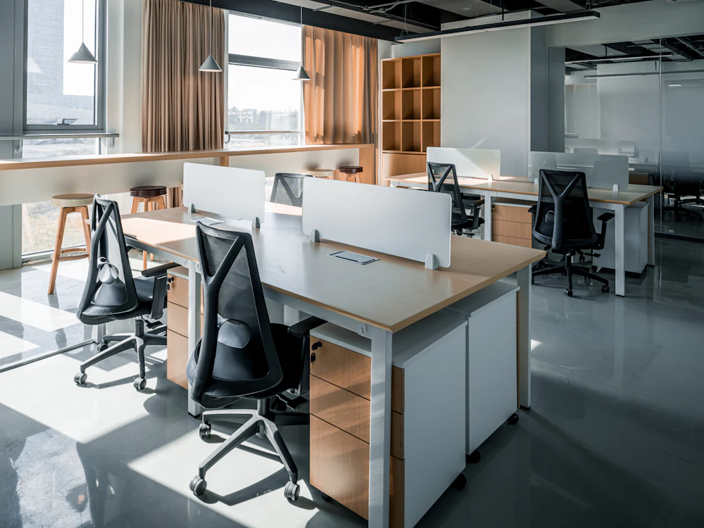 Estaciones de trabajo con escritorios y sillas de oficina junto a una ventana
